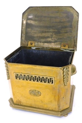 An Edwardian brass coal box, the canted rectangular lid enclosing a liner with a pierced frieze and a cast paterae, 38cm wide.