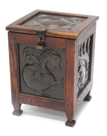 An early 20thC Arts and Crafts oak coal skuttle or box, applied with panels with hammered copper panels each side depicting roundels, squirrel, mythical beast, flower, and a bird, 34cm wide.