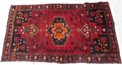 A Persian type rug, with a design of flowers, geometric devices, tendrils, etc, on a red ground with black spandrels, one wide and two narrow borders, (AF), 133cm wide, 240cm tall.