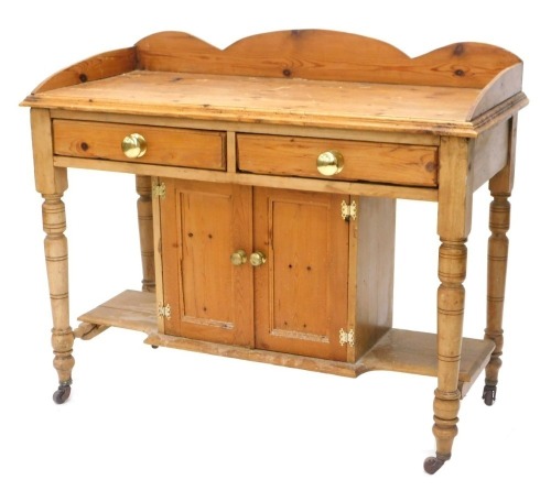 A late Victorian pine washstand, with a raised back above two frieze drawers and two cupboard doors, on turned legs with castors, 106cm wide.