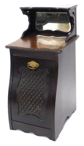 An Edwardian mahogany coal purdonium, the raised back with a shaped bevelled mirror, the base with a moulded edge and a fall front door carved with lattice design and a gilt metal handle, 38cm wide.