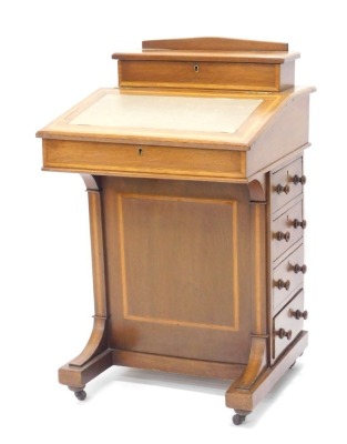 An Edwardian mahogany and satinwood banded Davenport, the raised top with a hinged recess for pens, etc., above a green leatherette mounted writing slope enclosing a fitted interior, with four drawers to the side and four false drawers, on shaped supports