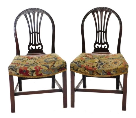 A pair of George III mahogany dining chairs, each with a hoop back carved with bell flowers, patera and a pierced splat, the woolwork tapestry padded seats on plain supports with H stretcher.