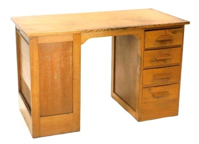 A mid 20thC oak office desk, with an arrangement of four drawers to one pedestal opposing a panel and with an unusual side tambour door, with sliding trays, each with various size divisions, 122cm wide.