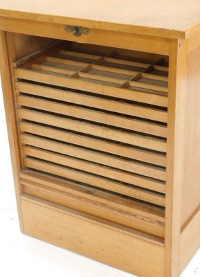 A mid 20thC oak office desk, with an arrangement of four drawers to one pedestal opposing a panel and with an unusual side tambour door, with sliding trays, each with various size divisions, 122cm wide. - 2