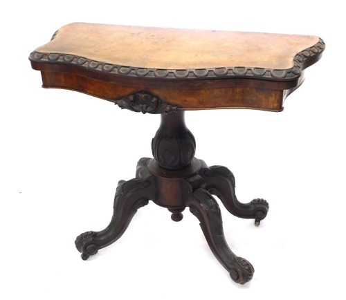 A Victorian figured mahogany card table, the serpentine shaped top with a carved edge, on a baluster shaped carved column and four splayed legs, 89cm wide.