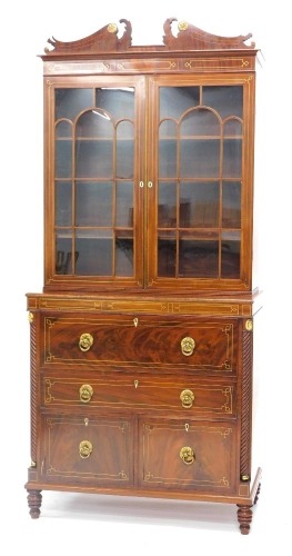 An early 19thC mahogany and brass secretaire bookcase, the top with a broken pediment above two astragal glazed doors, the base with a fall front fitted drawer enclosing fruitwood veneered interior, decorated centrally with a marquetry Britannia above a d