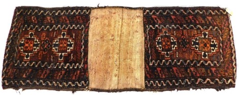 A Persian camelbag or juval, with a design of medallions, on a brown ground, with multicoloured geometric borders, some shells stitched to the outer border, 57cm x 147cm.