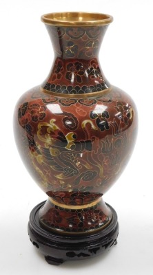 A Chinese red ground cloisonne vase, with stand, of baluster form, decorated with Imperial dragons chasing a flaming pearl, 20cm high, vase decorated with flowers on a black ground, 15.5cm high, and a vase decorated with peacocks on a blue ground, 15.5cm - 5