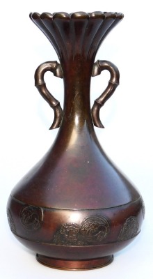 A Meiji period bronze vase, of fluted, and twin handled, baluster form, the body with a band embossed with prunus blossom and floral roundels, three character signature to base, 24.5cm high.