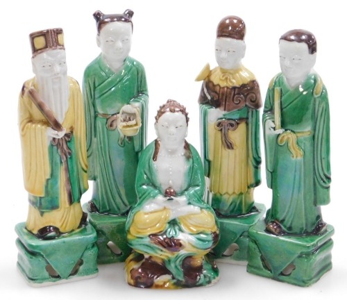 Five Qing dynasty sancai glazed figures, of a seated Buddha, 11cm high, and standing court officials on rectangular bases, 14.5cm high,