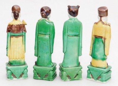 Five Qing dynasty sancai glazed figures, of a seated Buddha, 11cm high, and standing court officials on rectangular bases, 14.5cm high, - 6