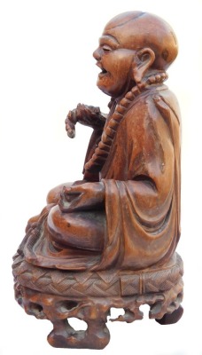 A late 19thC Chinese hardwood carving of a Buddha, seated on a lotus flower, 33cm high, and a pair of carvings of two women bat catchers, one seated, the other standing upon a shell, within a surround of bats and clouds, 38cm high. (3, AF) - 3