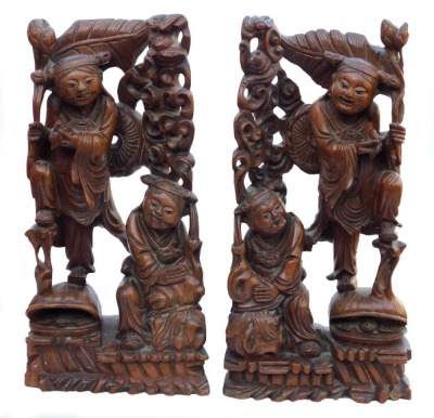 A late 19thC Chinese hardwood carving of a Buddha, seated on a lotus flower, 33cm high, and a pair of carvings of two women bat catchers, one seated, the other standing upon a shell, within a surround of bats and clouds, 38cm high. (3, AF) - 9