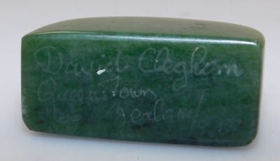 A jadeite pendant carved as the Happy Buddha, 5.5cm high, and a spinach jade carving, possibly a brush rest. (2) - 5