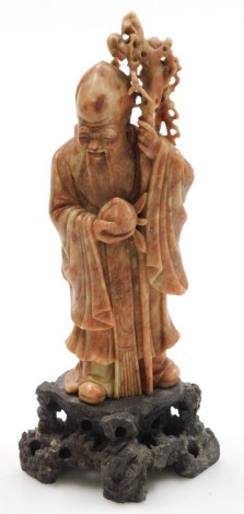 A Chinese soapstone figure of Shou Lao, God of Longevity, modelled standing holding a staff and a peach, on a rocky base, 25.5cm high.