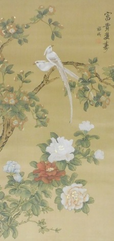 A 19thC Chinese watercolour on silk, of exotic birds in a blossoming tree, with peonies beneath, signed, framed and glazed, 101.5cm x 52.5cm.