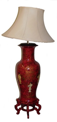 A Chinese red lacquer floor standing lamp, of baluster vase on stand, decorated with overlaid figures, on a ground with gilt pagodas, shade above, 174cm high.