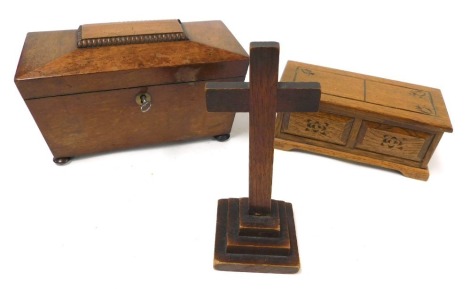 A Regency mahogany sarcophagus tea caddy, raised on bun feet, with key, 22.5cm wide, (AF), together with a Tallent musical jewellery chest, with engraved decoration, 18.5cm wide, and an oak cross, raised on a stepped base, 19cm high. (3)