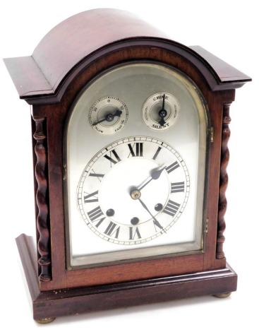 An Edwardian mahogany cased mantel clock, domed silvered dial, with chapter ring bearing Roman numerals, subsidiary chime, silent and slow/fast dials, eight day movement with Westminster chimes, the case of architectural form with barley twist columns, ra