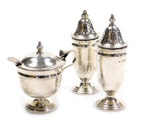 An Elizabeth II silver three piece condiment set, comprising salt, pepperette and mustard pot, no liners, Sheffield 1954, and spoon, 4.18oz.