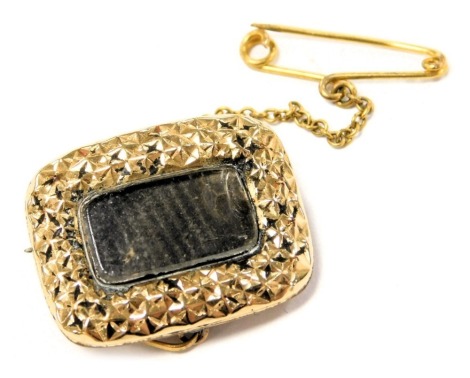 A Victorian hair locket brooch, in yellow metal, with engraved decoration, on safety chain, 4.9g.