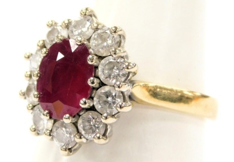 An 18ct gold ruby and diamond ring, the oval cut ruby in a surround of ten diamonds, ruby approximately 0.9 carats, diamonds approximately 1.25 carats, size P, 7.5g.