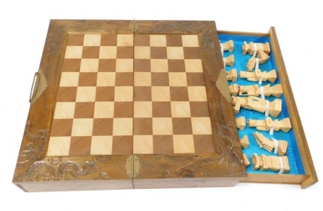 A Chinese carved boxed chess set, of hinged form, opening to reveal a chess board top, with two side drawers containing Chinese figural chess pieces, case 46cm wide.