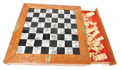 A Chinese carved boxed chess set, of hinged form, opening to reveal a chess board top, with two side drawers containing Chinese figural chess pieces, case 46cm wide.