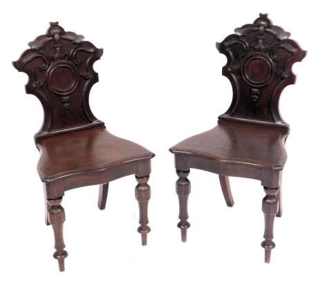 A pair of Victorian mahogany hall chairs, with shield shaped backs, serpentine seats, raised on turned legs.