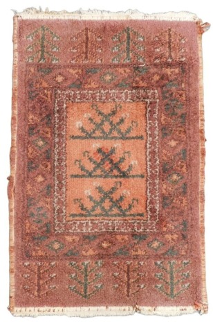 A Caucasian red ground rug, decorated with trees within floral borders, 85cm x 52cm.