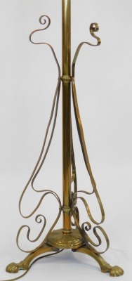 An Art Nouveau brass standard lamp, formerly an oil lamp later converted, with copper central reservoir on a cylindrical column, with scroll work adornments raised on four shell capped feet, with shade, 168cm high overall. - 3