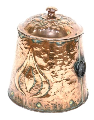 An Arts and Crafts copper lidded coal bin, of cylindrical tapering form with hammered decoration and foliate motif, with wrought iron ring handles, 44cm high.