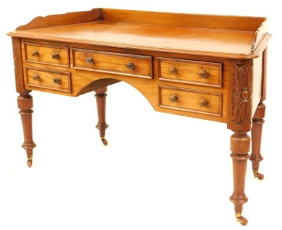 A Victorian mahogany dressing table, with canted sides, having shaped low gallery back and with thumb moulded border, fitted central drawer, above a knee hole flanked by two shallow drawers to each side, with carved foliate decoration to the corners above