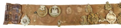 A canvas and leather belt containing various cap badges, to include Hampshire Regiment, Prince Albert's Own South Africa 1900-2, York and Lancaster Regiment, Dorsetshire Regiment, etc. together with a leather belt with buckle. - 3