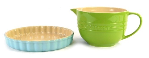 Two items of Le Creuset, comprising a green Le Creuset measuring cup, 12-02, 12cm high, and a turquoise oven ware flan dish, 1.35 litre, 25cm diameter. (2)