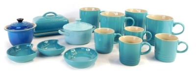 A group of Le Creuset homewares, comprising a set of four 0.35 litre light blue mugs, four 0.1 litre espresso mugs in pale blue, a turquoise butter dish and lid, and three pine dishes, and two miniature casserole dish. (1 tray)