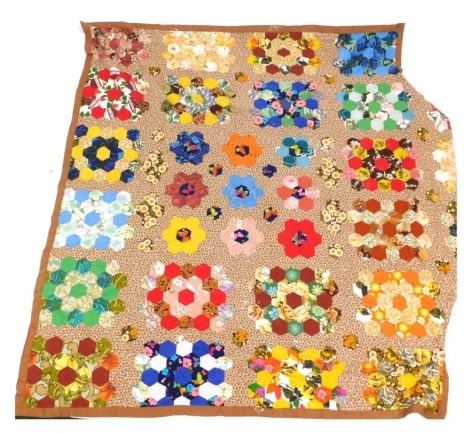 A patchwork quilt, with a brown material border, and hexagonal patchwork sections, approx 220cm x 250cm.