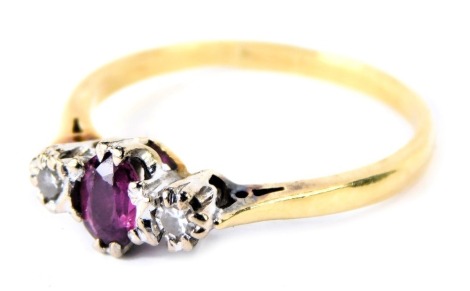 An 18ct gold ruby and diamond three stone dress ring, with central oval ruby in eight claw setting, flanked by two tiny diamonds each approx 0.03ct, in platinum setting on a yellow metal band, 2.9g all in.