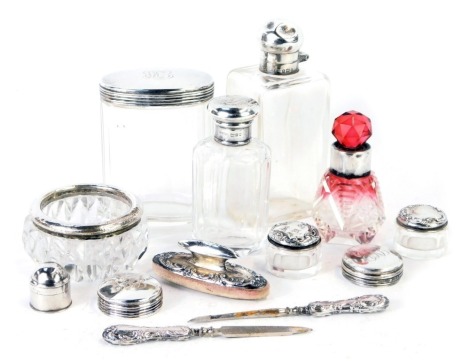 A group of silver topped dressing table jars, comprising a cut and cranberry glass silver rimmed scent bottle, two dressing table jars bearing the initials EKB, two miniature salts, manicure buffer and set, etc.