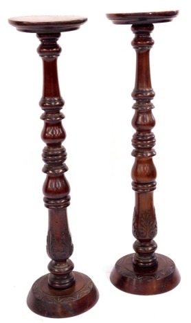 A pair of mahogany torcheres, each with turned columns, on a carved and leaf moulded base, 100cm high, 24cm diameter.