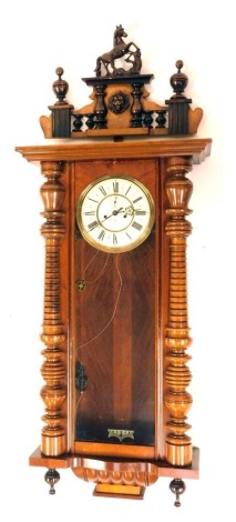 A 19thC mahogany Gustav Becker Vienna wall clock, with an arched pediment top, set with horse and lion mask, above reeded columns on bobbin supports, with a cream enamel Roman numeric dial and seconds dial, 112cm high, 50cm wide, 17cm deep.