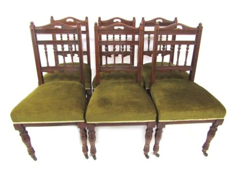 A set of six Edwardian mahogany dining chairs, each with a carved and turned column rail, overstuffed green upholstered seat, on turned tapering legs.