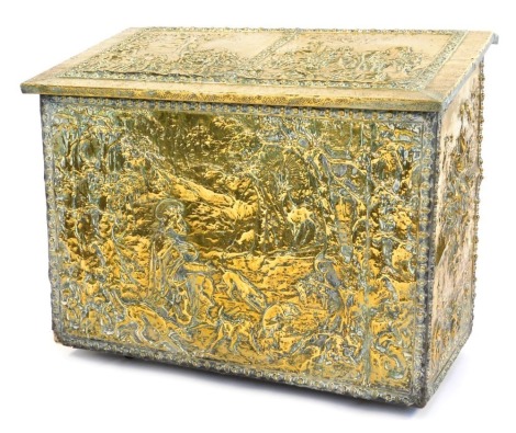 An embossed brass box, the hinged lid with panels of religious figures in woodland, with a two sectional fitted interior, on castors, 65cm high, 82cm wide, 44cm deep.