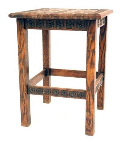 A 1920s carved oak table, the square top with cross and tulip design, 40cm high, the top 30cm x 30cm.