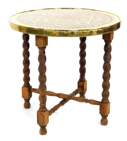 A Middle Eastern brass topped occasional table, with Arabic style design, on beech folding stand with barley twist legs, 56cm high, 60cm diameter.