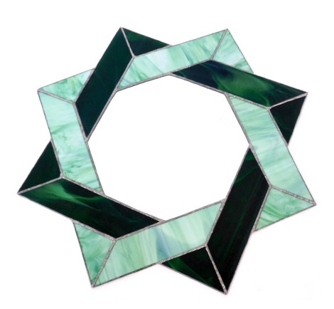 A green glass wall mirror, of star design with emerald and light green panels, 60cm diameter.