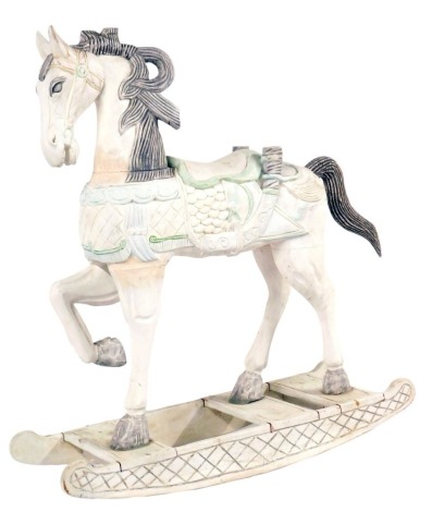 An Arabian style wooden rocking horse, with over-painted cream decoration, and a green lined saddle, 116cm high, 110cm wide, 42cm deep.