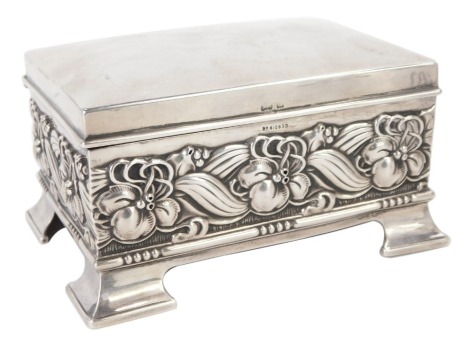 An Edward VII silver playing card box, embossed with a band of flowers and scrolling leaves, raised on bracket feet, with a red Morocco interior, Hawton & Allday, Birmingham 1903, 8.47oz all in, 12cm wide.