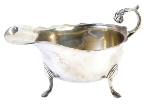 A George VI silver sauce boat, with foliate embossed scroll handle, raised on three hoof feet, Birmingham 1942, 3.41oz.